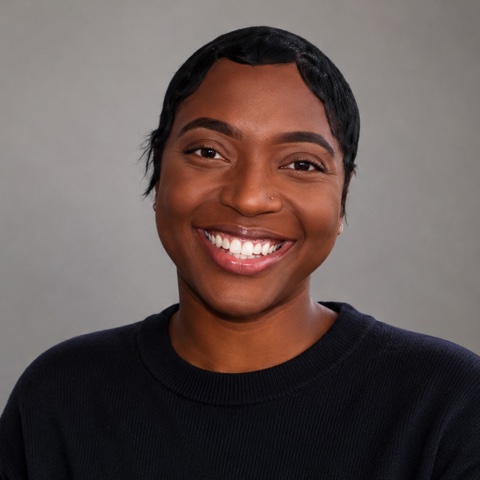 Portrait of Nadani Dixon, smiling, in a dark sweater